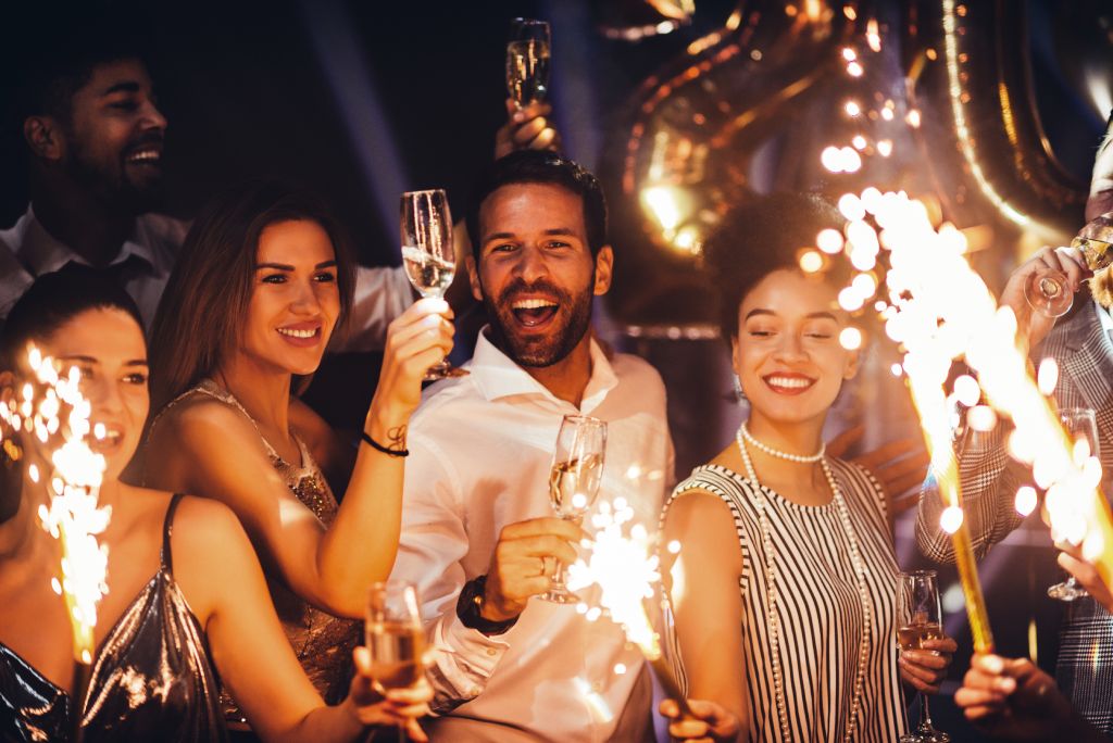 A photo of friends holding fire sparklers at a party.