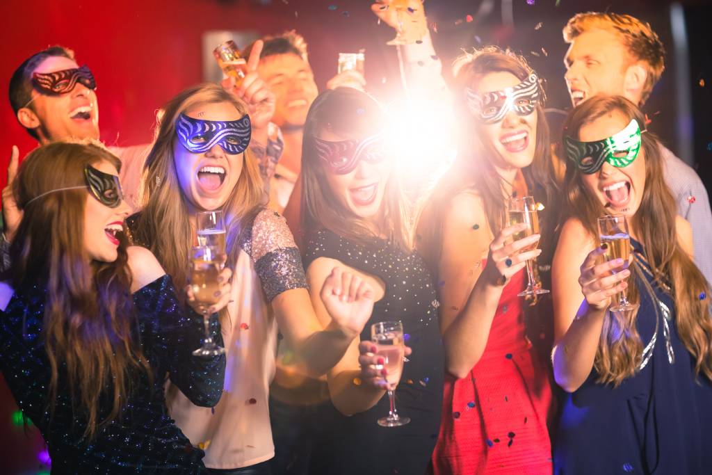 Friends at a nightclub drinking champagne in masquerade masks.